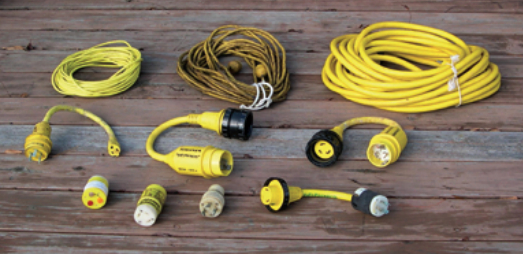 The contents of a typical shorepower bag, from left to right. Top row: cable-TV cord, telephone cord, 30A 125VAC power cord. Middle row: 30A 125VAC to 15A 125VAC adapter, 50A 125VAC to 30A 125VAC adapter, 50A 250/125VAC to 30A 125VAC adapter. Bottom row: polarity checker, 15A 125VAC to 30A 125VAC adapter, 30A 125VAC to 15A 125VAC adapter, 20A 125VAC to 30A 125VAC adapter. It’s a good idea to label the adapter with not only the type of socket it fits, but also with the name of your boat, so that on a marina dock there’s no question about who owns the adapter.