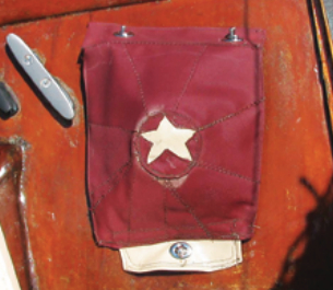 The tanbark-colored compass cover is made of leftover Sunbrella. The star decoration is cream-colored leather scavenged from an old office chair. The eyelet in the leather tab at the bottom can be secured to a twist-lock on the cabintop to expose the compass.