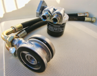A remote oil filter kit allows the filter to be placed in a more convenient location. The piece in the foreground replaces the filter on the engine block and the other piece is the filter mounting assembly.