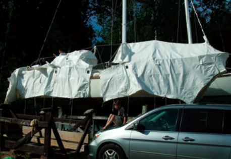 A downward slice at the mast separated the shrinkwrap into bow and stern sections. The stern section was the first to go. Two pairs of hands made an easier job of rolling the used shrinkwrap film into tight bundles. Asher Danicic, age 6, supervised and saved his dad from making multiple trips up and down the ladder.