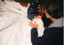 Someone sewing a sail