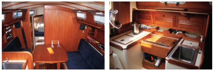 This view from the companionway shows the bulkhead-mounted table set up for use, at left. The U-shaped galley is quite complete for a 28-footer with stovetop, sink, icebox, and more-than-expected stowage, at right. High-quality joinerwork is evident throughout the boat.