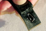 A simple turnbuckle lock can be made from a short length of wire and sticky-back Velcro, at top. The pin end of the wire pokes through the “hooked” Velcro and the loop holds it in position, at center. When the “fuzzy” Velcro is applied, the loop is held fast, at bottom. The combined Velcro strip sticks to itself when wrapped around the turnbuckle, holding the pin in the screw.
