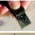 A simple turnbuckle lock can be made from a short length of wire and sticky-back Velcro, at top. The pin end of the wire pokes through the “hooked” Velcro and the loop holds it in position, at center. When the “fuzzy” Velcro is applied, the loop is held fast, at bottom. The combined Velcro strip sticks to itself when wrapped around the turnbuckle, holding the pin in the screw.