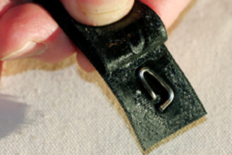 A simple turnbuckle lock can be made from a short length of wire and sticky-back Velcro, at top. The pin end of the wire pokes through the “hooked” Velcro and the loop holds it in position, at center. When the “fuzzy” Velcro is applied, the loop is held fast, at bottom. The combined Velcro strip sticks to itself when wrapped around the turnbuckle, holding the pin in the screw.