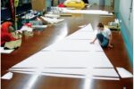 Components of Sailrite sail kits are computer cut, including the corner reinforcement patches, above. Isaiah Grant (the third generation of the Grant family to enter the business) is shown here laying out the panels for a genoa.