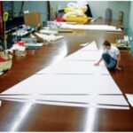 Components of Sailrite sail kits are computer cut, including the corner reinforcement patches, above. Isaiah Grant (the third generation of the Grant family to enter the business) is shown here laying out the panels for a genoa.