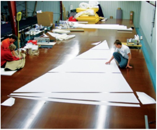 Components of Sailrite sail kits are computer cut, including the corner reinforcement patches, above. Isaiah Grant (the third generation of the Grant family to enter the business) is shown here laying out the panels for a genoa.