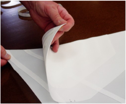 The entire assembly is then positioned on the sail with the largest patch on top and sewn in place.