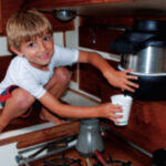 David’s grandson Jake demonstrates how a height-challenged but nimble crewmember obtains a draught of fresh water from the communal scuttlebutt aboard Ariel.