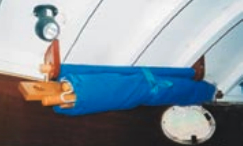 The Catnapper, rolled up and secured close to the overhead with Velcro on a nylon strap. The three H-frame pieces and the dowel for the foot are all rolled up in it. Note the reading spotlight above the right shoulder.