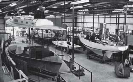 At Morgan Yachts’ St. Petersburg, Florida, facility, men worked from scaffolding on boats of all sizes. Note how the decks were moved and positioned from overhead beams.