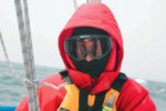 A picture of someone bundled up from the cold on a boat