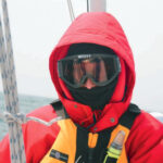 A picture of someone bundled up from the cold on a boat