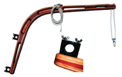 Rail clamps, such as those used to mount horseshoe buoy brackets, work well for attaching the davits to the stern rail. The davit is a complete assembly with rail clamps, a cleat for belaying the lifting line, and sheave, ready for mounting on the stern rail. The lifting line is running from its dead end at the hole in the end of the davit, down through a block with carabiner attached, up over the sheave, and finally back to the cleat. Note that the solid wood spacers are placed to provide solid backing for attached hardware such as the rail clamps, the cleat where the spreader bar attaches, and the sheave for the lifting line.