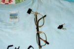 Paper clamps, also called binder clips, are readily available in different colors. An arm of the eyeglasses slips through the exposed lever of the paper clamp to adhere to securely to a shirt collar.