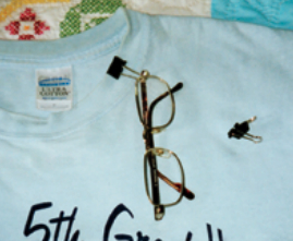 Paper clamps, also called binder clips, are readily available in different colors. An arm of the eyeglasses slips through the exposed lever of the paper clamp to adhere to securely to a shirt collar.