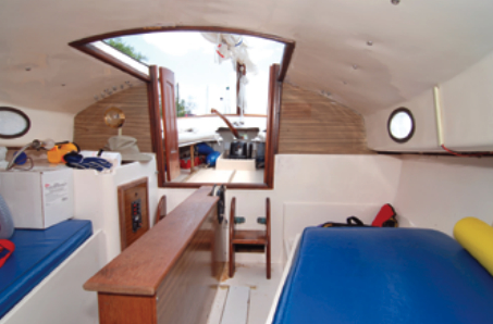 Twin companionway ladders lead to a compact galley to starboard, two bunks and a portable toilet to port.