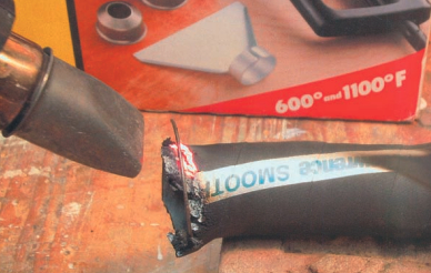 The 1,100° F setting on the heat gun chars this black rubber exhaust hose sample, just as it did to the epoxy/fiberglass laminate. However, in this case, it also produced glowing embers but did not flame. This hose carries the SAE J2006 certification and meets ABYC standards, while the slightly less flammable epoxy/fiberglass laminate does not.