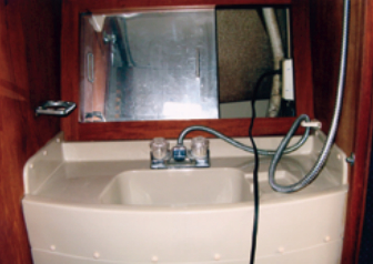 The head compartment on Liza extends completely across the boat, making possible this conveniently large lavatory with mirror-faced cabinet behind.