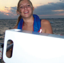 Jyllian at the helm in 2005. The white object in the foreground is Michael’s homemade nav station.