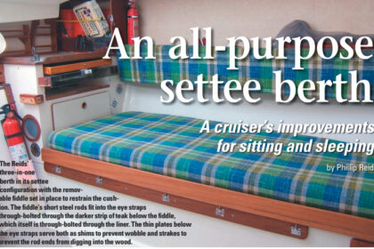 The Reids’ three-in-one berth in its settee configuration with the removable fiddle set in place to restrain the cushion. The fiddle’s short steel rods fit into the eye straps through-bolted through the darker strip of teak below the fiddle, which itself is through-bolted through the liner. The thin plates below the eye straps serve both as shims to prevent wobble and strakes to prevent the rod ends from digging into the wood.