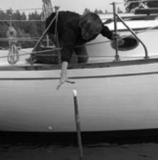 Beth retrieving the boathook, which is floating vertically.