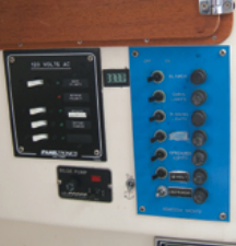 The 120-volt, 30-amp shorepower service and breaker panel and the original 12-volt DC distribution panel. The anchor-light switch is off the panel. Between the two panels is a Datel digital voltmeter. It cost only $30 and has served well for five years.