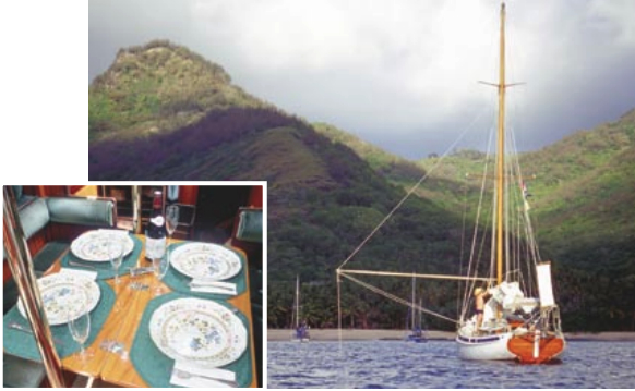 Taleisin at anchor in the Marquesas Islands, flopper-stopper set to cut down the rolling. The Pardeys celebrated the end of their second circumnavigation here after crossing their outboard track. Though their boat is modest, the Pardeys are not without luxuries aboard, as evidenced by the table set for dinner in the main cabin (inset).