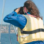 Picture of a woman using binoculars on a boat