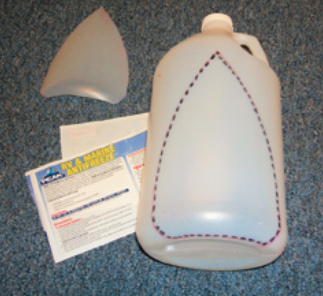 The basic materials for making a shrink-wrap vent are shrinkwrap tape (not shown) and a clean empty plastic jug. Cut a shape depicted by the dotted lines, making sure to leave some of the jug bottom on for stiffness. Cut two of these pieces from each jug.