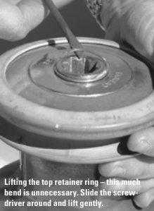 Lifting the top retainer ring – this much bend is unnecessary. Slide the screwdriver around and lift gently.