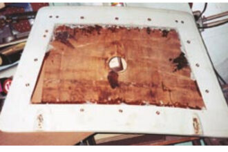 The job begins with a router cut, above, to allow for the removal of the top fiberglass layer. Next, the fiberglass skin is peeled back and the wet core is removed, at center, ready for a replacement layer of Masonite. While curing, the repair is clamped through the center hole, bottom.
