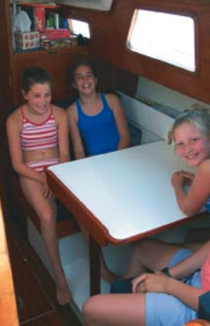Author Tom Young’s daughter, Mary Jane, at left, visits Jack’s daughter, Abey, seated next to her, and her friend, Hilary Gordon, aboard Sunrise. The new dinette table works well for the three girls and one adult.