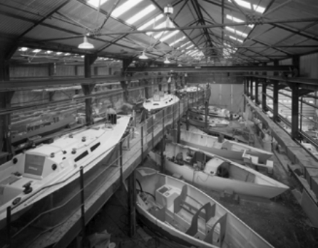 In 1979, Camper & Nicholsons’ “B” shed had several models of production fiberglass sailboats under construction. From the foreground looking back is a Nicholson 33 hull, two 35s, a 32, and a 31. To the left is a deck for the 33 and behind it two decks for 35s.