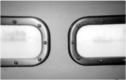John Karklins’ finished portlights above. He recommends against using polycarbonate. It gets cloudy, as the illustration shows. The teak spacer he added to compensate for the additional thickness of his “armor-plated windows” shows around the edges of the frame.