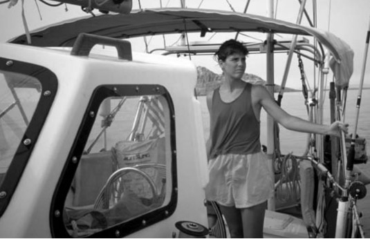 woman standing next to hard dodger on a sailboat