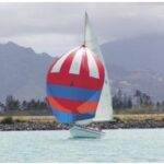 The Rhodes 19, christened in 1971 by group members as Wet Hen, glides across a Honolulu backdrop.