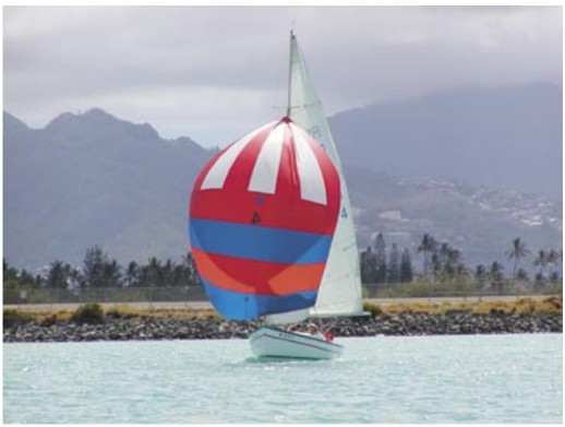 The Rhodes 19, christened in 1971 by group members as Wet Hen, glides across a Honolulu backdrop.