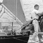 Al Petersen stands on footropes with his knees securely around the bowsprit. Note how Al has tied off the staysail boom to keep it out of mischief while he is nearby. This is the bow of Stornoway, the 33-foot cutter that Al sailed around the world.