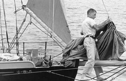 Al Petersen stands on footropes with his knees securely around the bowsprit. Note how Al has tied off the staysail boom to keep it out of mischief while he is nearby. This is the bow of Stornoway, the 33-foot cutter that Al sailed around the world.