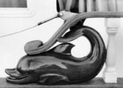 What fun to see this delightful carving going to sea. Some anonymous woodworker with the soul of an artist has turned the forward end of this taffrail into a thing of pleasure and beauty. Any clod could have screwed a piece of wood between the upper and lower rails, but only an inspired artist could have fashioned this frolicking figure for all the world to see and admire.