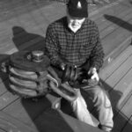 Who’s this gnome? We don’t mean to frighten you, but look what happened to Don Launer before he learned to give his wooden blocks regular maintenance. Actually, he says the large one, which weighs more than 90 pounds, was used to hoist cargo aboard a World War II Liberty Ship.