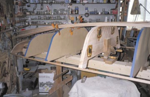 The forms in place atop the strongback. The center come-apart bulkhead is constructed first, complete with hardware, and attached as one unit. The boat is essentially built whole and then cut in half. It is good to leave a bit of space between the bow and stern bulkheads to accommodate the saw blade when cutting the strips. It is very important to get the dinghy forms straight and parallel before you start to strip. Any mistake here will be amplified later on. Take your time and measure the distance between forms on both sides to make sure they agree.