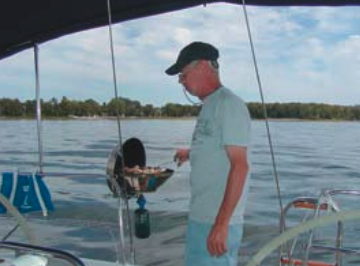 A member of the Tuesday-evening racing crew, Dave Michalkiewicz, uses the grill on Another Adventure, author Barry Hammerberg’s 1990 Hunter Legend 35.5. The propane bottle is stored on the stern pulpit in a mesh bag.