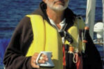 Picture of a man sailing with a cup of coffee in his hand