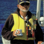 Picture of a man sailing with a cup of coffee in his hand