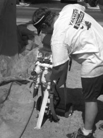 The operator connects his hoses to the soda-blasting equipment.