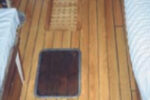 Replacing the teak cabin sole was one of Ken’s projects on his Allied Seabreeze 35 yawl, at top. He chose a cheery red oak for the conversion. When he substituted the old hatch for the newer replacement, at right center, the difference in color between the worn teak and the new oak floor covering was striking. An earlier step in that sole conversion, at right, also shows the contrast between the two woods.