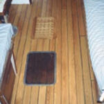 Replacing the teak cabin sole was one of Ken’s projects on his Allied Seabreeze 35 yawl, at top. He chose a cheery red oak for the conversion. When he substituted the old hatch for the newer replacement, at right center, the difference in color between the worn teak and the new oak floor covering was striking. An earlier step in that sole conversion, at right, also shows the contrast between the two woods.